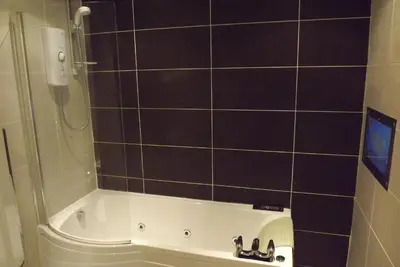 a bathroom with a shower and a tub with a sink at Glazert Country House Hotel in Lennoxtown