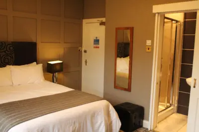 a bedroom with a bed and a mirror and a window at Glazert Country House Hotel in Lennoxtown