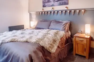 a bedroom with a bed and a table with a lamp at Cottage Apartment in Dunblane