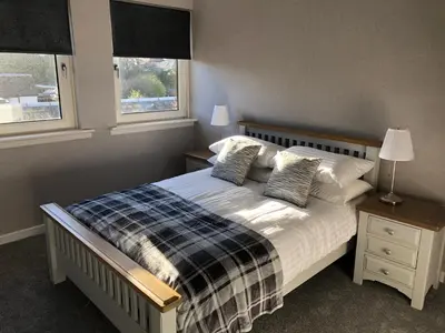 a bedroom with a bed and two windows at Old Police House Causewayhead Stirling in Stirling