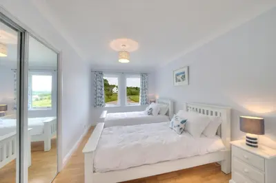 a white bedroom with two beds and a window at Seabank House in Oban