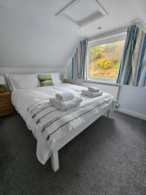 a white bed in a room with a window at Seabank House in Oban