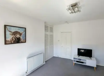 a room with a television and a painting of a bull on the wall at Bespoke Tours Scotland Accommodation @ Morrison Street in Edinburgh