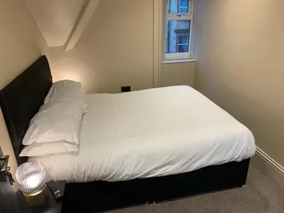 a bedroom with a bed with white sheets and a window at Raniven in Oban