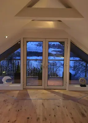 a room with large windows with a view of the water at Invercreran Lodge Luxury Bed & Breakfast in Appin