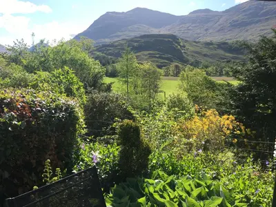 a view of a garden with mountains in the background at Invercreran Lodge Luxury Bed & Breakfast in Appin