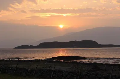 a sunset over the water with mountains in the background at Sealladh in Port Appin