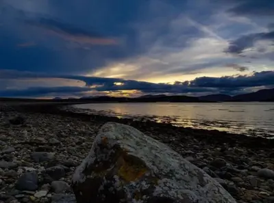 a rock sitting on the shore of a body of water at Sealladh in Port Appin