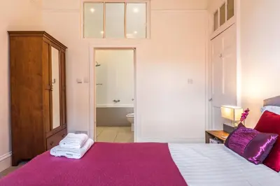 a bedroom with a bed with a purple blanket at Charming, Central & Spacious Georgian 3 bed APT in Edinburgh