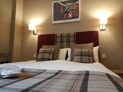 a bedroom with a large bed with two pillows at The Fairburn Hotel in Mauchline