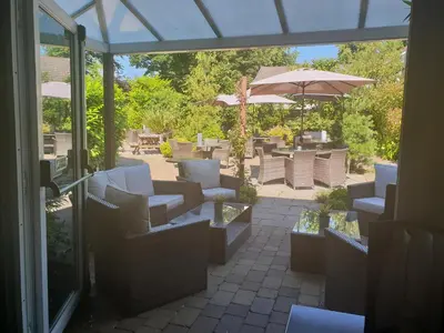 a patio with white chairs and an umbrella and tables at The Fairburn Hotel in Mauchline