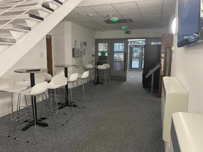 a waiting room with stools and tables and stairs at Premier Lodge in Falkirk