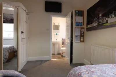a bedroom with a bed and a bathroom with a sink at The Trout Fly Guest House in Port Ellen