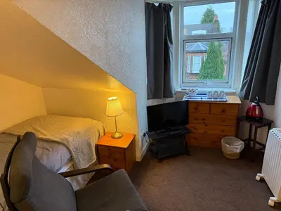 a bedroom with a bed and a tv and a window at Glades House in Glasgow