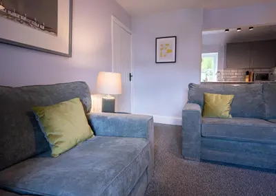 a living room with two blue couches and a lamp at One Oban in Oban