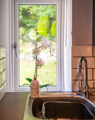 a kitchen sink with a vase of flowers in a window at One Oban in Oban