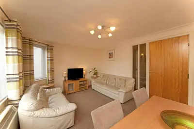 a living room with two white couches and a television at 3 Albany Apartments - Oban in Oban