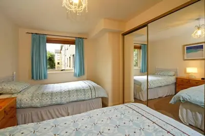 a bedroom with two beds and a mirror at 3 Albany Apartments - Oban in Oban