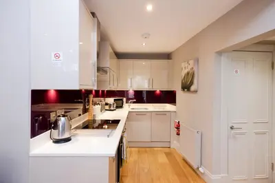 a kitchen with white cabinets and a white counter top at JOIVY Splendid Flat near Edinburgh Castle in Edinburgh