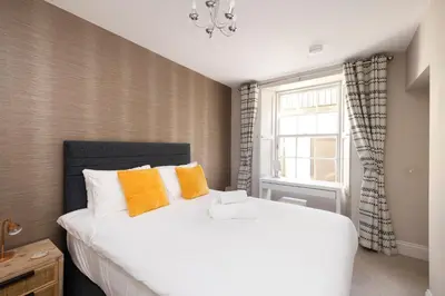 a bedroom with a large white bed with orange pillows at JOIVY Splendid Flat near Edinburgh Castle in Edinburgh