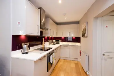 a kitchen with white cabinets and wooden floors at JOIVY Splendid Flat near Edinburgh Castle in Edinburgh