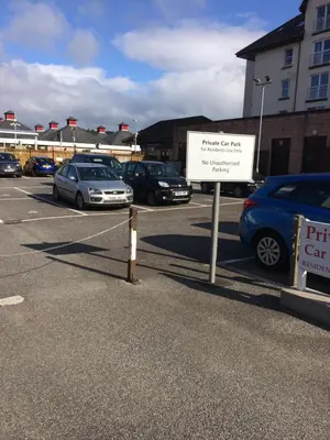 a sign in a parking lot with cars parked at Lismore House in Oban