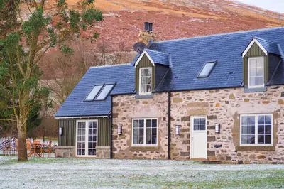 a stone house with a blue roof and windows at Dalveich Cottage, hot tub, 2 bedroom, Lochearnhead in Lochearnhead