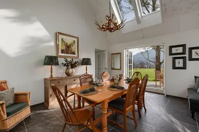a dining room with a wooden table and chairs at Dalveich Cottage, hot tub, 2 bedroom, Lochearnhead in Lochearnhead