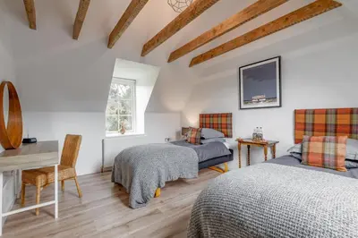 a bedroom with two beds and a desk at Dalveich Cottage, hot tub, 2 bedroom, Lochearnhead in Lochearnhead