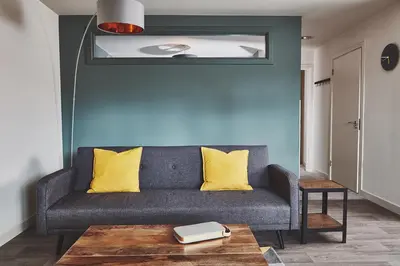 a living room with a gray couch with yellow pillows at The Ranald Apartments in Oban