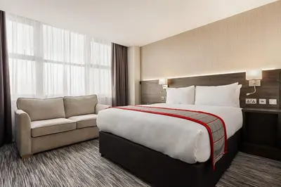 a hotel room with a large bed and a couch at Ramada East Kilbride in East Kilbride