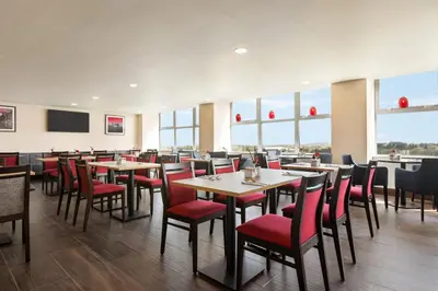 a dining room with tables and red chairs at Ramada East Kilbride in East Kilbride