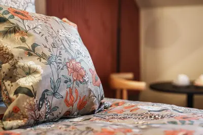 a pillow sitting on top of a bed with flowers at Bonnie Hotel - Smart Boutique ApartHotel - Haymarket Edinburgh in Edinburgh
