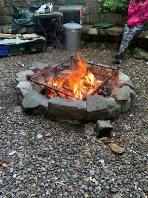 a fire pit with a person sitting next to it at The West Highland Way Hotel and Retreat Accommodation in Glasgow