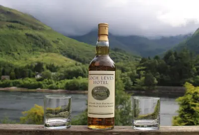 a bottle of hot legs hotel next to two glasses at Loch Leven Hotel & Distillery in Glencoe