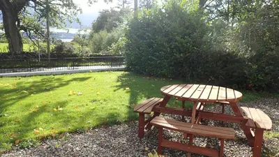 a wooden picnic table and bench in a park at Arrochoile in Balmaha