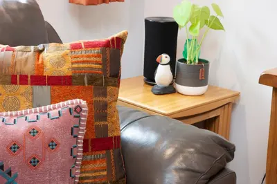 a leather couch with a pillow and a penguin on a table at Mandarin Premier Apartments D 2 Bed Apt 1st Floor in Oban