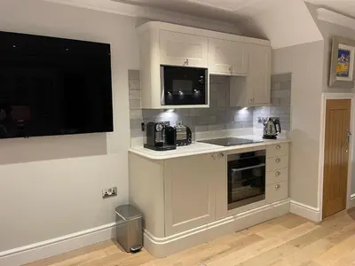 a kitchen with white cabinets and a flat screen tv at Bagpipers Luxury Hideaway Glencoe Ballachulish Highlands Near Fort William in Glencoe