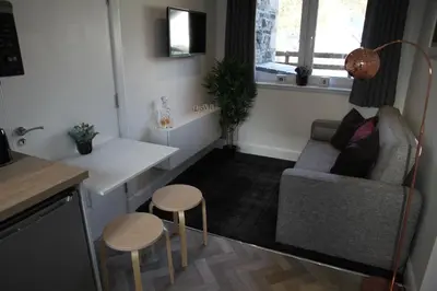 a living room with a couch and a table and two stools at The Wee Bank House in Oban