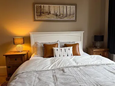 a bedroom with a white bed with pillows and a painting at Murrayfield Spacious 2-bedroom apartment in Edinburgh
