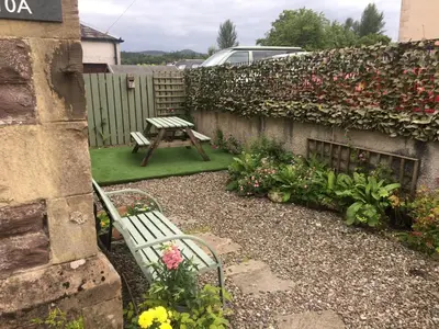 a garden with a bench and a table and flowers at The old post office Callander holiday let in Callander