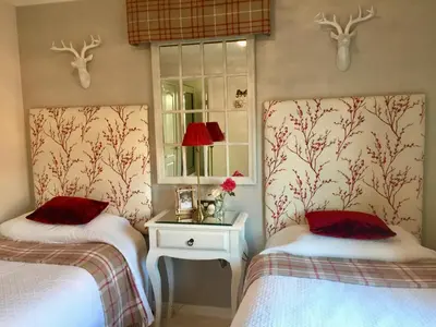 two twin beds in a room with deer heads on the wall at Otter Lodge Auchterarder in Auchterarder