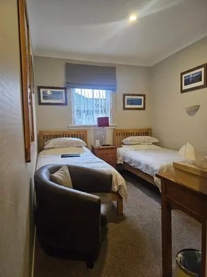 a bedroom with two beds and a couch and a chair at Whitecroft B&B in Edinburgh