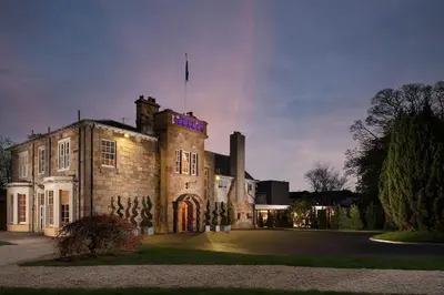 an old building with a flag on top of it at Dalmeny Park House Hotel in Barrhead