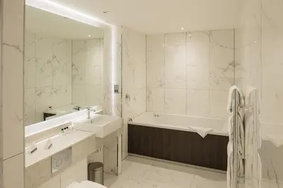 a white bathroom with a tub and a sink and a bath tubermott at Dalmeny Park House Hotel in Barrhead