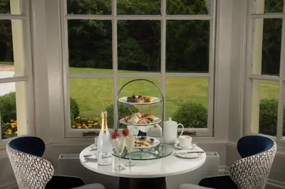 a table with a plate of food on it next to a window at Dalmeny Park House Hotel in Barrhead