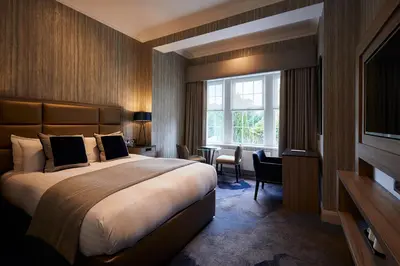 a hotel room with a large bed and a window at Dalmeny Park House Hotel in Barrhead