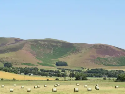 a field of hay with mountains in the background at Blueacres in Skirling