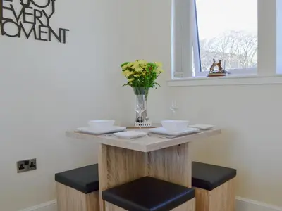 a table with two stools and a vase with flowers at Blueacres in Skirling