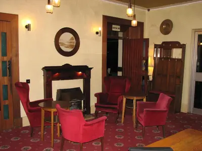 a room with chairs and tables and a fireplace at Lancaster Hotel in Oban
